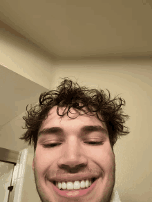 a man with curly hair and a beard is smiling