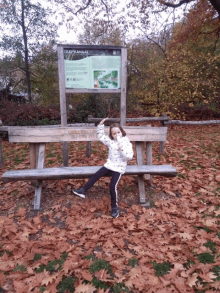 a little girl sitting on a wooden bench in front of a sign that says oud-kanaal