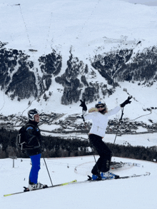 two skiers are standing on a snowy slope with one wearing a helmet that says prada