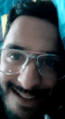 a man with glasses and a beard is smiling for the camera .