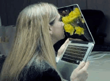 a woman is holding a laptop with a picture of flowers on the screen .