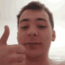 a shirtless man gives a thumbs up in a blurry photo