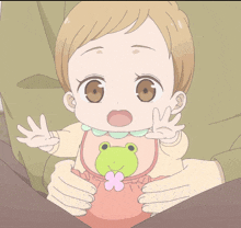 a baby wearing a bib with a frog on it is being held by a person