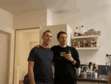 two men are posing for a picture in a kitchen with one wearing a black shirt that says l' occitane