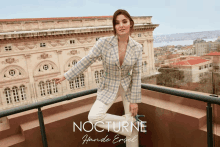 a woman is standing on a balcony with the word nocturne on the bottom right