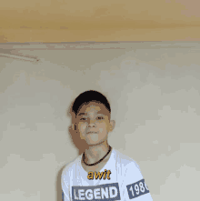 a boy wearing a white shirt with legend on it