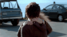 a woman holds a man 's neck in front of a car with a license plate that starts with a s on it