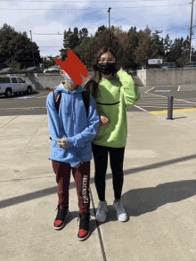 a girl wearing a green sweatshirt stands next to a boy wearing a blue shirt