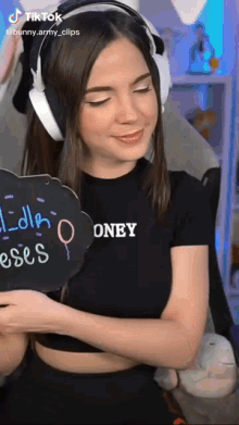 a woman wearing headphones is holding a sign that says " oney "