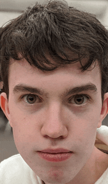 a close up of a young man 's face with a white shirt