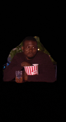 a man is holding a bucket of popcorn and a glass of beer