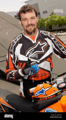 a man wearing an alpinestars shirt is sitting on a motorcycle