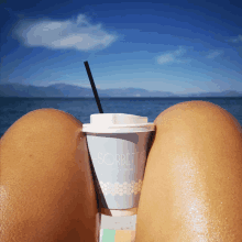 a woman sits on the beach with a cup of sorbetto on her lap