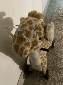 a stuffed giraffe wearing glasses sits on wheels