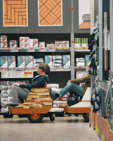 a man and a woman sit on a cart in a store with a sign that says ' brick ' on it