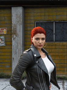 a woman in a leather jacket stands in front of a yellow building with a sign that says " no smoking "