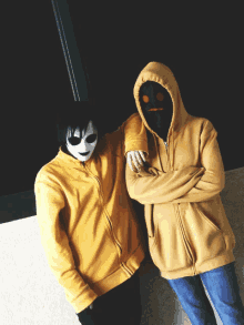 two people wearing masks and hoodies are posing for a picture