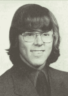 a young man wearing glasses and a suit is smiling for the camera