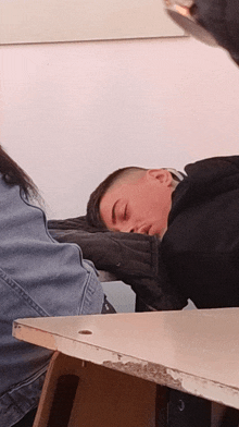 a young man sleeping on a desk with his eyes closed