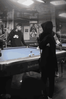 a man wearing a nike sweatshirt is playing pool