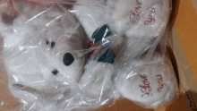 a white teddy bear is wrapped in plastic and says i love you on its paws