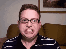 a man with glasses and a striped shirt is making a funny face