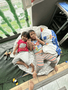 two children laying on a blanket one of whom is wearing a thailand shirt