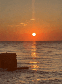 a sunset over a body of water with the sun shining through the clouds