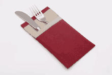 a knife and fork in a red and tan napkin