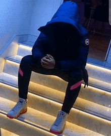 a person in a blue jacket is sitting on a set of stairs .