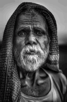 a man with a beard and a scarf around his head looks at the camera