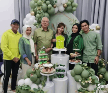 a group of people are posing for a picture in front of a cake display