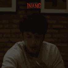 a man is smoking a cigarette in a dark room with the word inang on the bottom