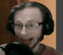 a man wearing headphones and glasses is speaking into a microphone .