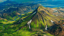 an aerial view of a mountain covered in green grass and snow