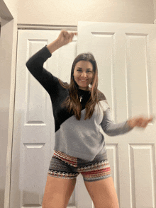 a woman in shorts is dancing in front of a door