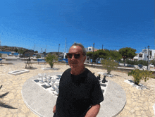 a man in sunglasses stands in front of a large chess board