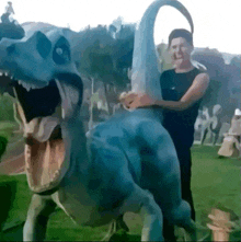 a man is standing next to a dinosaur statue .