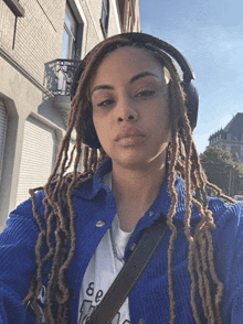 a woman with dreadlocks wearing headphones and a t-shirt that says ee