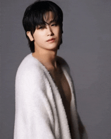 a young man without a shirt is wrapped in a white furry sweater