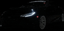 a black car is parked in the dark with the lights on