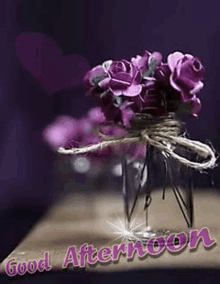 a vase filled with purple roses is on a table with the words `` good afternoon '' written on it .