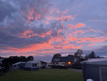 a sunset over a campground with tents and a house