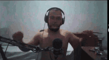 a man without a shirt is wearing headphones and holding a microphone