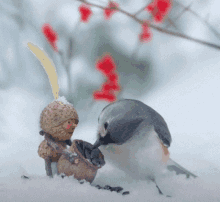 a small figurine of a bird wearing an acorn hat feeds a smaller figurine of a bird