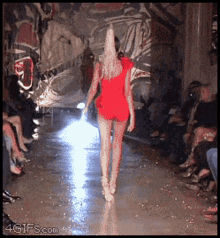 a woman in a red dress is walking down the runway