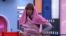 a man is wrapped in a pink towel while standing on a stage .