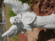 a white statue of a woman with wings is laying on the ground