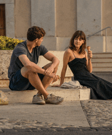 a woman in a black dress is eating an ice cream cone