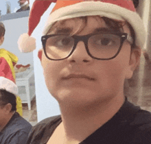 a young boy wearing glasses and a santa hat is making a funny face .